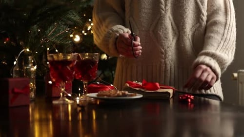 Person Wrapping Christmas Present at Decorated Table