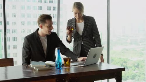 Empresária e empresário se reunindo com um laptop que parece e discutindo juntos.