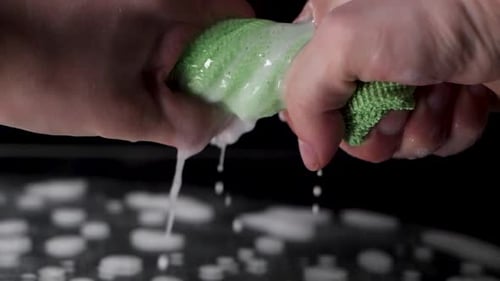 Extreme close up wring out a green rag in slow motion.