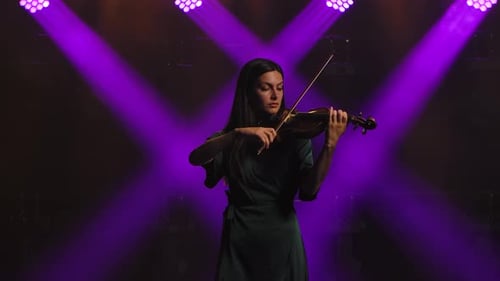 Woman Plays Violin on Stage with Purple Lights