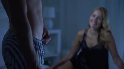 Woman Smiles at Man in Bedroom at Night