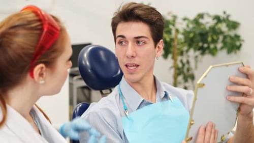 Young Man Talking with Female Dentist Before Teeth Whitening Procedure