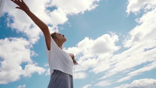 Woman Enjoying Fresh Air Under Cloudy Blue Sky