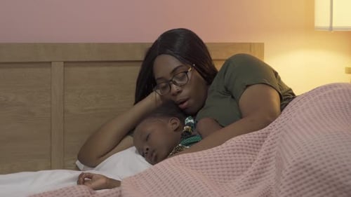 Mother Resting Beside Sleeping Child in Bed
