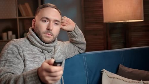 Pensive Lonely Man Sitting on Couch Watching Tv Set Switch Channel Relaxing at Home Winter Evening