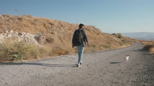 Man walking on the dirt road with a dog