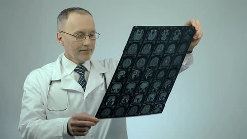 Doctor Looking at MRI Brain Scan, Satisfied With Patient's Positive Dynamics