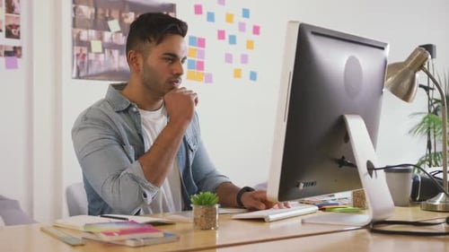 Mann gemischter Abstammung arbeitet am Computer im Kreativbüro
