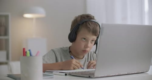 Boy Studying at Desk With Laptop and Notebook