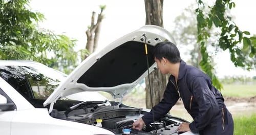 Asian automobile mechanic check engine oil level