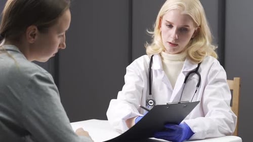 Female Doctor Consults with Patient, Takes Notes