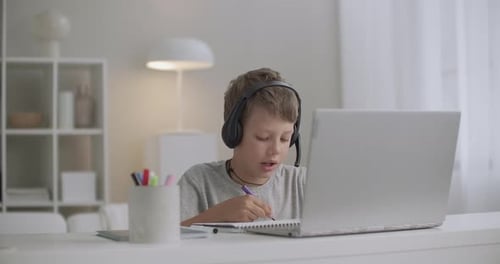 Young Blond Boy Studying at Laptop with Headphones