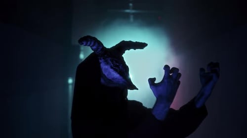 Dark Hooded Figure with Horned Mask Gesturing