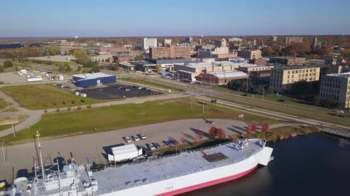 Aerial view of ship on river, streets and buildings in Muskegon, MI