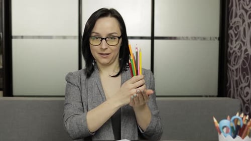 Woman Talking and Holding Paper and Pencils