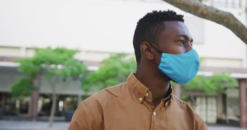 African american businessman wearing face mask sitting in park