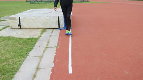 Tiefer Ausschnitt einer Sportlerin beim Messen des Hochsprungfeldes mit einer Schrittweite von 4k