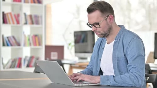 Man Typing on Laptop in Office Environment