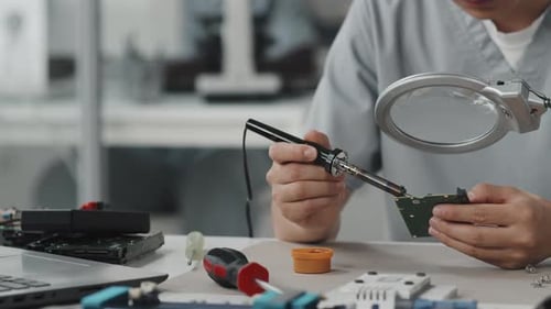 Technician Soldering Circuit Board in Workplace