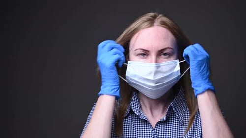 Woman Removing Surgical Mask with Blue Gloves