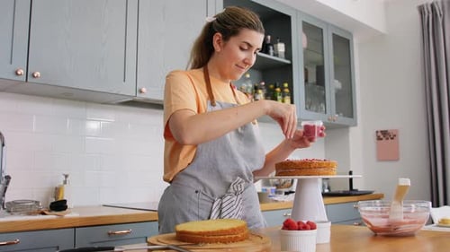 Woman decorating a cake in her bright kitchen