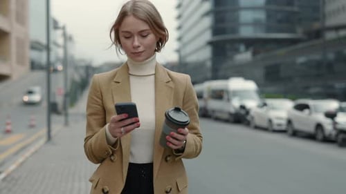 Woman Walking with Phone and Coffee in City