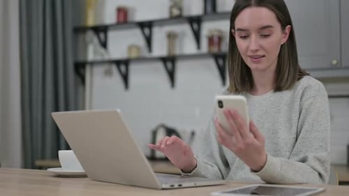 Woman Uses Laptop and Smartphone at Desk