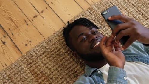 Mann liegt mit Smartphone auf dem Boden