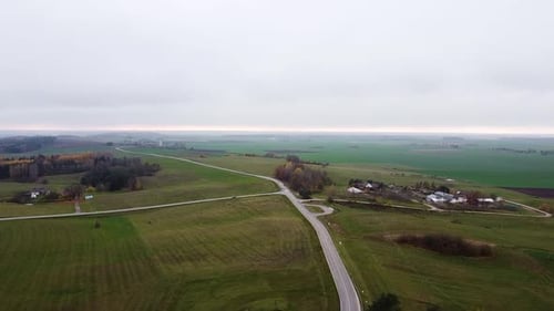 Luftaufnahme einer kleinen, aber langen Landstraße mit grüner Wiese, die sie umgibt.