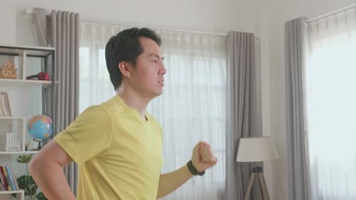 Seitenansicht eines asiatischen Mannes, der zu Hause auf einem Laufband läuft