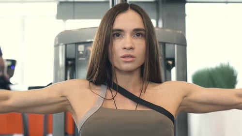 Young Beautiful Muscular Woman Bodybuilder Is Engaged In Gym And With Dumbbells
