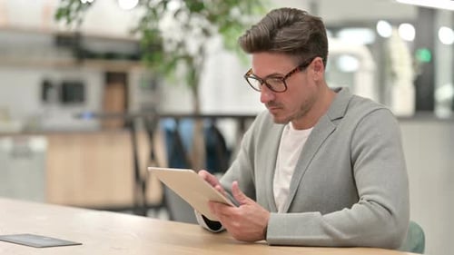 Pensive Middle Aged Man Using Tablet in Office