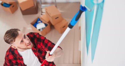 Nahaufnahme Porträt eines fröhlichen jungen Mannes in einer neuen Wohnung, die Zimmer renoviert, Gemälde Wand mit