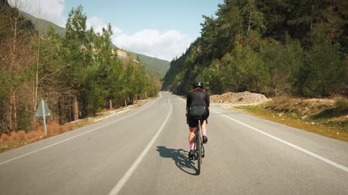 Professional cyclist riding bicycle up through mountain pass.