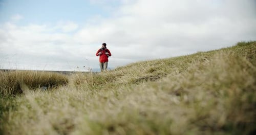 View of a Man Legs in Boots Walking on Green Moss and Grass in Iceland.