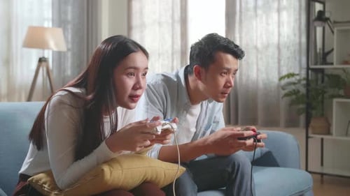 Couple Playing Video Games Together on Couch Indoors