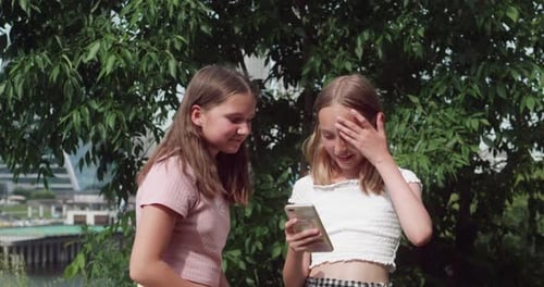Girls Using Smartphone Together in City Park