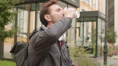 Man Drinks Coffee Outside in Urban Setting