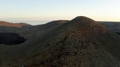 Leute sitzen auf einem Berg und beobachten einen Vulkan