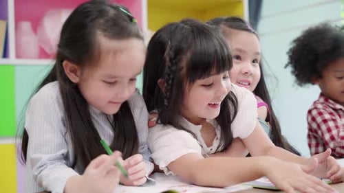 Multi-ethnic young boys and girls happy funny study and play painting on paper at elementary school.