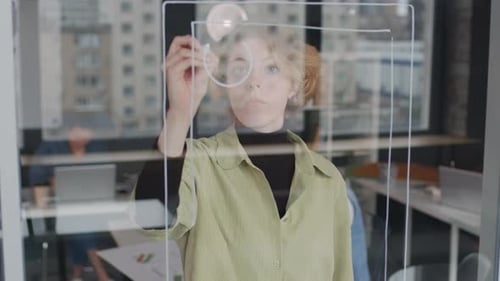 Woman Designs Wireframe on Transparent Screen in Office