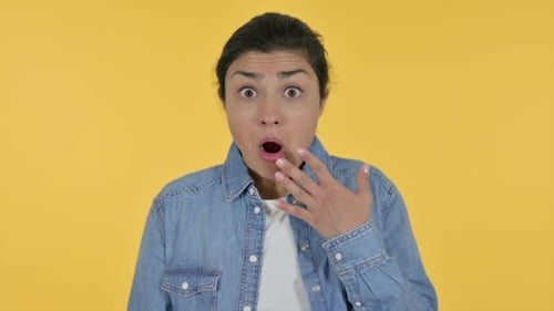 Woman with surprised expression against yellow background