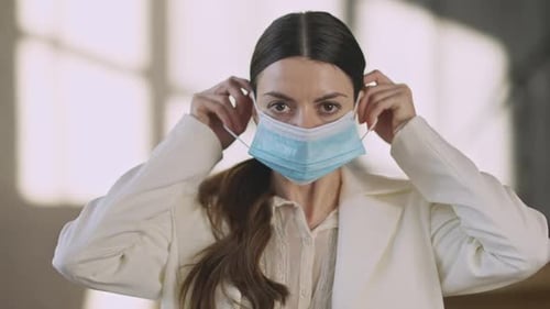 Woman Puts on a Blue Surgical Mask