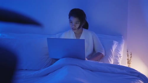 Woman Works on Laptop Late at Night in Bed