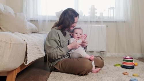 Ein glückliches Kind spielt mit seiner Mutter auf dem Teppich im Wohnzimmer Pastetchen. Kleinkind Baby Junge lächelt
