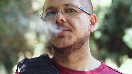 Homme chauve caucasien allumant une cigarette- en plein air