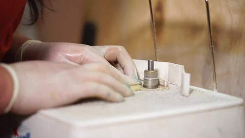 Craftsperson Smooths Material on Rotating Cylinder