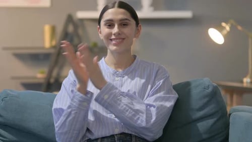 Young Woman Smiling and Clapping on Couch