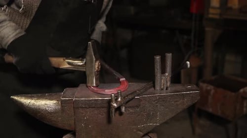 Close Up Shot of a Blacksmith's Hand, Who Hammers a Horseshoe in the Workshop