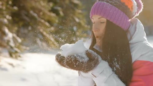 Woman Blowing Snow in Snowy Winter Forest